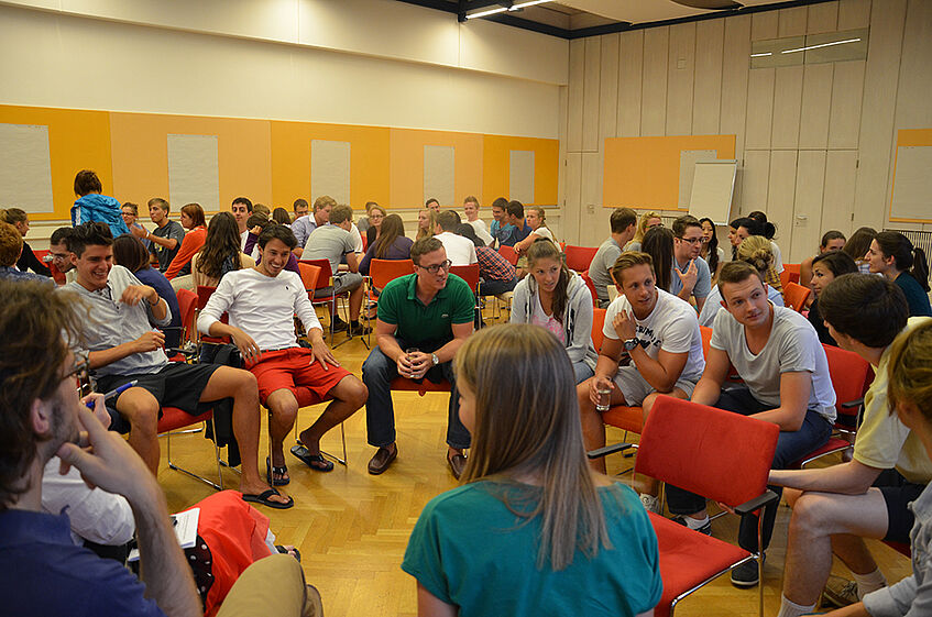 Students sitting in circles in a lecture hall, discussion in small Groups.