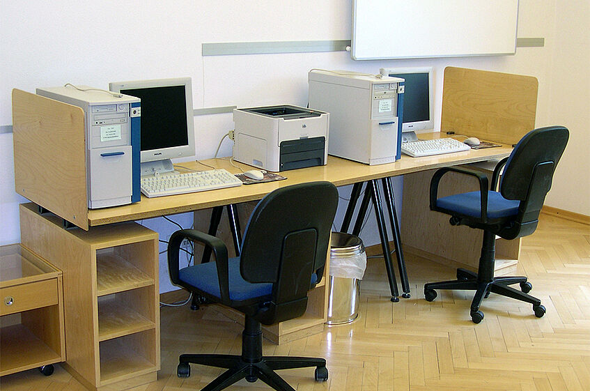 Two desks somplete with computers, screens, keyboard and mouse.
