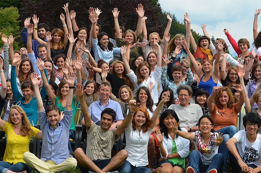 Group picture of the participants of 2012 waving their hands in the air