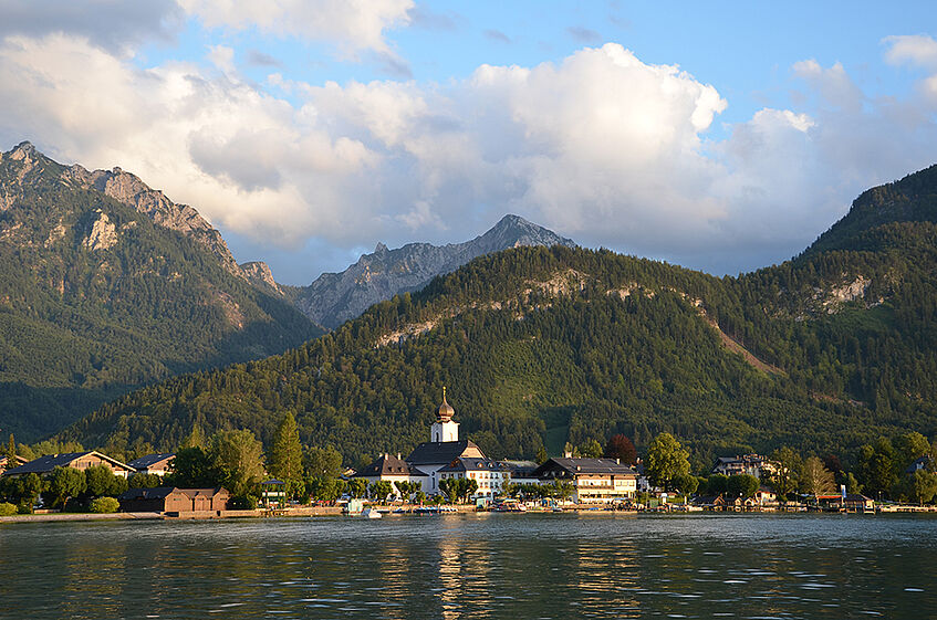 View of the village Strobl nestled between lake Wolfgang in the front and a mountain range in the back.