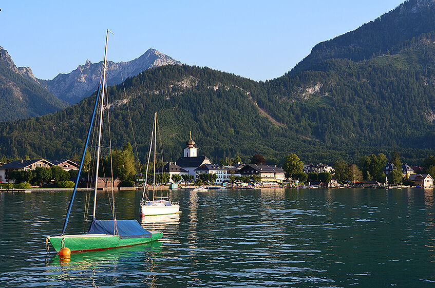 View of the village Strobl, the lake with boats in the front and mountains in the background.