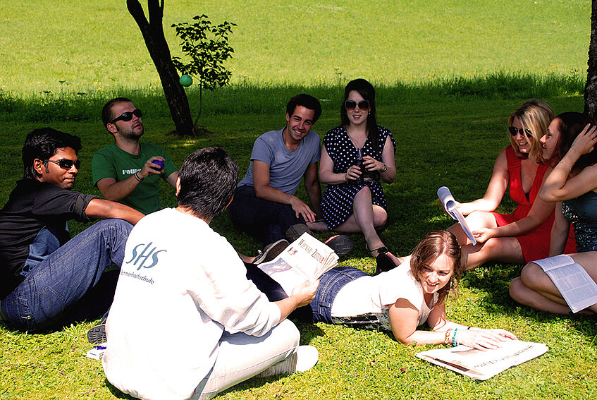 A group of students sitting chatting in a circle on the meadow 