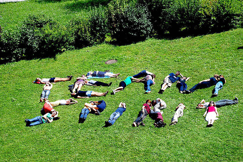 Students lying on lawn and forming the words 