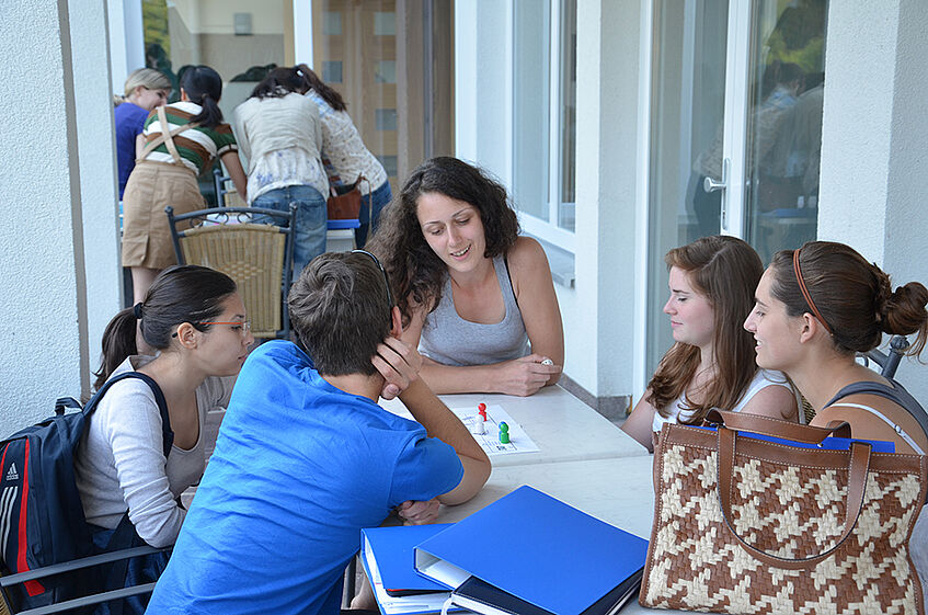 Five students sitting around a table playing an eucational game.